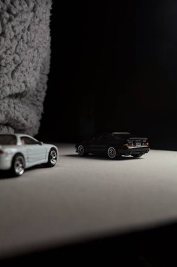 Mantova, İtalya - 3RD JANUARY 2025 - 1989 Mazda Savanna RX-7 'nin Ateşli Tekerlekleri ve Kibrit kutusu kopyaları ve beyaz bir tahtanın üzerinde beyaz bir kumaş parçasının yanında, uçurumun kenarındaki bir dağ yolunda yarış yapıyormuş gibi yapan Mitsubishi 3000 GT