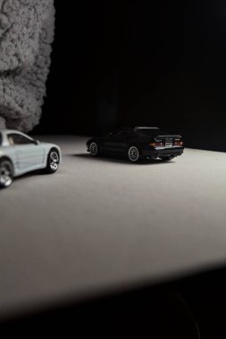 Mantova, İtalya - 3RD JANUARY 2025 - 1989 Mazda Savanna RX-7 'nin Ateşli Tekerlekleri ve Kibrit kutusu kopyaları ve beyaz bir tahtanın üzerinde beyaz bir kumaş parçasının yanında, uçurumun kenarındaki bir dağ yolunda yarış yapıyormuş gibi yapan Mitsubishi 3000 GT