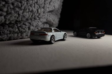 Mantova, İtalya - 3RD JANUARY 2025 - 1989 Mazda Savanna RX-7 'nin Ateşli Tekerlekleri ve Kibrit kutusu kopyaları ve beyaz bir tahtanın üzerinde beyaz bir kumaş parçasının yanında, uçurumun kenarındaki bir dağ yolunda yarış yapıyormuş gibi yapan Mitsubishi 3000 GT