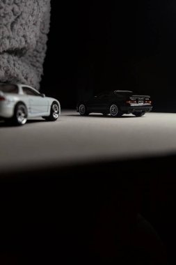 Mantova, İtalya - 3RD JANUARY 2025 - 1989 Mazda Savanna RX-7 'nin Ateşli Tekerlekleri ve Kibrit kutusu kopyaları ve beyaz bir tahtanın üzerinde beyaz bir kumaş parçasının yanında, uçurumun kenarındaki bir dağ yolunda yarış yapıyormuş gibi yapan Mitsubishi 3000 GT