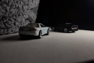 Mantova, İtalya - 3RD JANUARY 2025 - 1989 Mazda Savanna RX-7 'nin Ateşli Tekerlekleri ve Kibrit kutusu kopyaları ve beyaz bir tahtanın üzerinde beyaz bir kumaş parçasının yanında, uçurumun kenarındaki bir dağ yolunda yarış yapıyormuş gibi yapan Mitsubishi 3000 GT