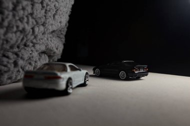 Mantova, İtalya - 3RD JANUARY 2025 - 1989 Mazda Savanna RX-7 'nin Ateşli Tekerlekleri ve Kibrit kutusu kopyaları ve beyaz bir tahtanın üzerinde beyaz bir kumaş parçasının yanında, uçurumun kenarındaki bir dağ yolunda yarış yapıyormuş gibi yapan Mitsubishi 3000 GT