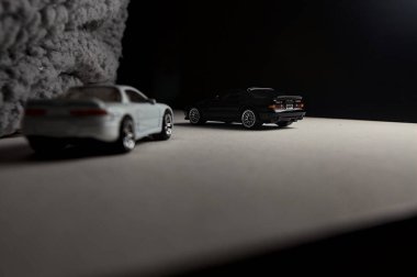 Mantova, İtalya - 3RD JANUARY 2025 - 1989 Mazda Savanna RX-7 'nin Ateşli Tekerlekleri ve Kibrit kutusu kopyaları ve beyaz bir tahtanın üzerinde beyaz bir kumaş parçasının yanında, uçurumun kenarındaki bir dağ yolunda yarış yapıyormuş gibi yapan Mitsubishi 3000 GT