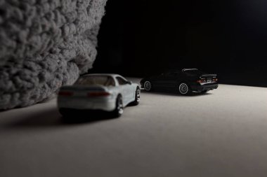 Mantova, İtalya - 3RD JANUARY 2025 - 1989 Mazda Savanna RX-7 'nin Ateşli Tekerlekleri ve Kibrit kutusu kopyaları ve beyaz bir tahtanın üzerinde beyaz bir kumaş parçasının yanında, uçurumun kenarındaki bir dağ yolunda yarış yapıyormuş gibi yapan Mitsubishi 3000 GT