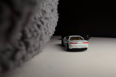 Mantova, İtalya - 3RD JANUARY 2025 - 1989 Mazda Savanna RX-7 'nin Ateşli Tekerlekleri ve Kibrit kutusu kopyaları ve beyaz bir tahtanın üzerinde beyaz bir kumaş parçasının yanında, uçurumun kenarındaki bir dağ yolunda yarış yapıyormuş gibi yapan Mitsubishi 3000 GT