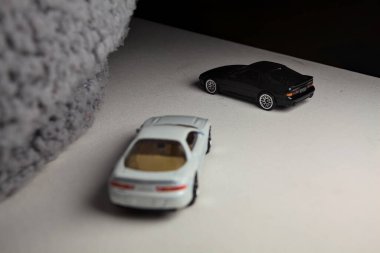 Mantova, İtalya - 3RD JANUARY 2025 - 1989 Mazda Savanna RX-7 'nin Ateşli Tekerlekleri ve Kibrit kutusu kopyaları ve beyaz bir tahtanın üzerinde beyaz bir kumaş parçasının yanında, uçurumun kenarındaki bir dağ yolunda yarış yapıyormuş gibi yapan Mitsubishi 3000 GT