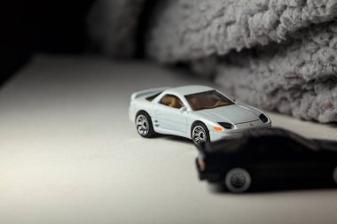 Mantova, İtalya - 3RD JANUARY 2025 - 1989 Mazda Savanna RX-7 'nin Ateşli Tekerlekleri ve Kibrit kutusu kopyaları ve beyaz bir tahtanın üzerinde beyaz bir kumaş parçasının yanında, uçurumun kenarındaki bir dağ yolunda yarış yapıyormuş gibi yapan Mitsubishi 3000 GT