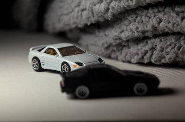 Mantova, İtalya - 3RD JANUARY 2025 - 1989 Mazda Savanna RX-7 'nin Ateşli Tekerlekleri ve Kibrit kutusu kopyaları ve beyaz bir tahtanın üzerinde beyaz bir kumaş parçasının yanında, uçurumun kenarındaki bir dağ yolunda yarış yapıyormuş gibi yapan Mitsubishi 3000 GT