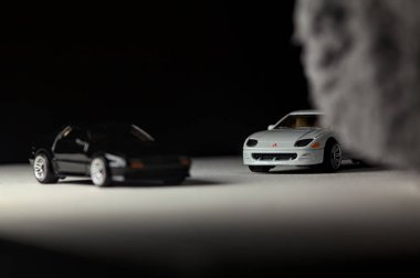 Mantova, İtalya - 3RD JANUARY 2025 - 1989 Mazda Savanna RX-7 'nin Ateşli Tekerlekleri ve Kibrit kutusu kopyaları ve beyaz bir tahtanın üzerinde beyaz bir kumaş parçasının yanında, uçurumun kenarındaki bir dağ yolunda yarış yapıyormuş gibi yapan Mitsubishi 3000 GT