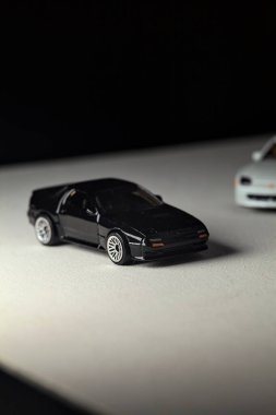 Mantova, İtalya - 3RD JANUARY 2025 - 1989 Mazda Savanna RX-7 'nin Ateşli Tekerlekleri ve Kibrit kutusu kopyaları ve beyaz bir tahtanın üzerinde beyaz bir kumaş parçasının yanında, uçurumun kenarındaki bir dağ yolunda yarış yapıyormuş gibi yapan Mitsubishi 3000 GT