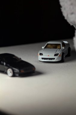 Mantova, İtalya - 3RD JANUARY 2025 - 1989 Mazda Savanna RX-7 'nin Ateşli Tekerlekleri ve Kibrit kutusu kopyaları ve beyaz bir tahtanın üzerinde beyaz bir kumaş parçasının yanında, uçurumun kenarındaki bir dağ yolunda yarış yapıyormuş gibi yapan Mitsubishi 3000 GT