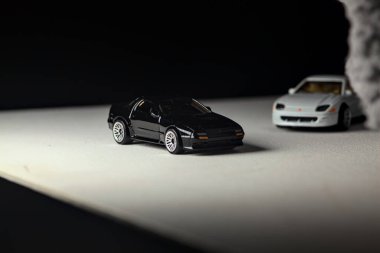 Mantova, İtalya - 3RD JANUARY 2025 - 1989 Mazda Savanna RX-7 'nin Ateşli Tekerlekleri ve Kibrit kutusu kopyaları ve beyaz bir tahtanın üzerinde beyaz bir kumaş parçasının yanında, uçurumun kenarındaki bir dağ yolunda yarış yapıyormuş gibi yapan Mitsubishi 3000 GT