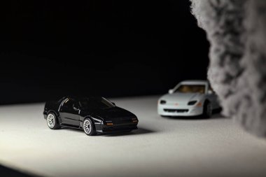 Mantova, İtalya - 3RD JANUARY 2025 - 1989 Mazda Savanna RX-7 'nin Ateşli Tekerlekleri ve Kibrit kutusu kopyaları ve beyaz bir tahtanın üzerinde beyaz bir kumaş parçasının yanında, uçurumun kenarındaki bir dağ yolunda yarış yapıyormuş gibi yapan Mitsubishi 3000 GT