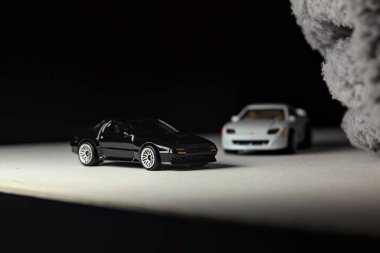 Mantova, İtalya - 3RD JANUARY 2025 - 1989 Mazda Savanna RX-7 'nin Ateşli Tekerlekleri ve Kibrit kutusu kopyaları ve beyaz bir tahtanın üzerinde beyaz bir kumaş parçasının yanında, uçurumun kenarındaki bir dağ yolunda yarış yapıyormuş gibi yapan Mitsubishi 3000 GT