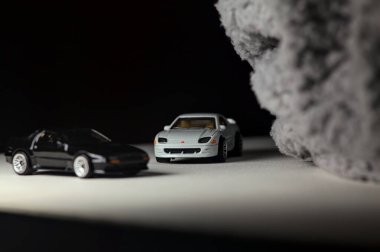 Mantova, İtalya - 3RD JANUARY 2025 - 1989 Mazda Savanna RX-7 'nin Ateşli Tekerlekleri ve Kibrit kutusu kopyaları ve beyaz bir tahtanın üzerinde beyaz bir kumaş parçasının yanında, uçurumun kenarındaki bir dağ yolunda yarış yapıyormuş gibi yapan Mitsubishi 3000 GT