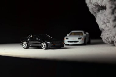 Mantova, İtalya - 3RD JANUARY 2025 - 1989 Mazda Savanna RX-7 'nin Ateşli Tekerlekleri ve Kibrit kutusu kopyaları ve beyaz bir tahtanın üzerinde beyaz bir kumaş parçasının yanında, uçurumun kenarındaki bir dağ yolunda yarış yapıyormuş gibi yapan Mitsubishi 3000 GT