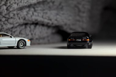 Mantova, İtalya - 3RD JANUARY 2025 - 1989 Mazda Savanna RX-7 'nin Ateşli Tekerlekleri ve Kibrit kutusu kopyaları ve beyaz bir tahtanın üzerinde beyaz bir kumaş parçasının yanında, uçurumun kenarındaki bir dağ yolunda yarış yapıyormuş gibi yapan Mitsubishi 3000 GT