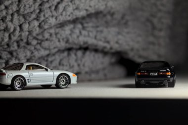 Mantova, İtalya - 3RD JANUARY 2025 - 1989 Mazda Savanna RX-7 'nin Ateşli Tekerlekleri ve Kibrit kutusu kopyaları ve beyaz bir tahtanın üzerinde beyaz bir kumaş parçasının yanında, uçurumun kenarındaki bir dağ yolunda yarış yapıyormuş gibi yapan Mitsubishi 3000 GT