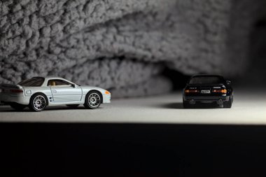 Mantova, İtalya - 3RD JANUARY 2025 - 1989 Mazda Savanna RX-7 'nin Ateşli Tekerlekleri ve Kibrit kutusu kopyaları ve beyaz bir tahtanın üzerinde beyaz bir kumaş parçasının yanında, uçurumun kenarındaki bir dağ yolunda yarış yapıyormuş gibi yapan Mitsubishi 3000 GT