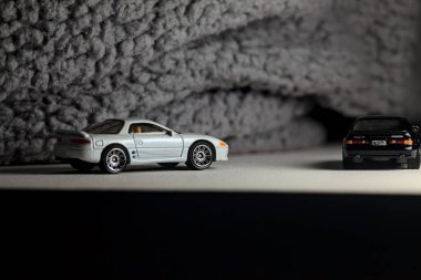 Mantova, İtalya - 3RD JANUARY 2025 - 1989 Mazda Savanna RX-7 'nin Ateşli Tekerlekleri ve Kibrit kutusu kopyaları ve beyaz bir tahtanın üzerinde beyaz bir kumaş parçasının yanında, uçurumun kenarındaki bir dağ yolunda yarış yapıyormuş gibi yapan Mitsubishi 3000 GT