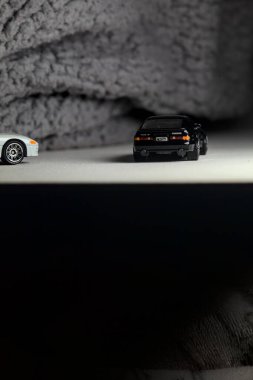 Mantova, İtalya - 3RD JANUARY 2025 - 1989 Mazda Savanna RX-7 'nin Ateşli Tekerlekleri ve Kibrit kutusu kopyaları ve beyaz bir tahtanın üzerinde beyaz bir kumaş parçasının yanında, uçurumun kenarındaki bir dağ yolunda yarış yapıyormuş gibi yapan Mitsubishi 3000 GT