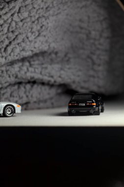 Mantova, İtalya - 3RD JANUARY 2025 - 1989 Mazda Savanna RX-7 'nin Ateşli Tekerlekleri ve Kibrit kutusu kopyaları ve beyaz bir tahtanın üzerinde beyaz bir kumaş parçasının yanında, uçurumun kenarındaki bir dağ yolunda yarış yapıyormuş gibi yapan Mitsubishi 3000 GT