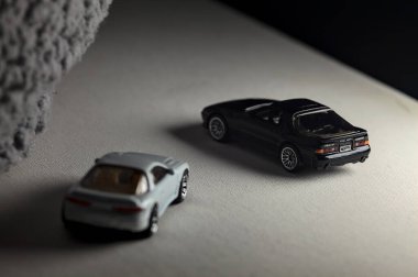 Mantova, İtalya - 3RD JANUARY 2025 - 1989 Mazda Savanna RX-7 'nin Ateşli Tekerlekleri ve Kibrit kutusu kopyaları ve beyaz bir tahtanın üzerinde beyaz bir kumaş parçasının yanında, uçurumun kenarındaki bir dağ yolunda yarış yapıyormuş gibi yapan Mitsubishi 3000 GT