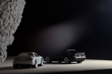 Mantova, İtalya - 3RD JANUARY 2025 - 1989 Mazda Savanna RX-7 'nin Ateşli Tekerlekleri ve Kibrit kutusu kopyaları ve beyaz bir tahtanın üzerinde beyaz bir kumaş parçasının yanında, uçurumun kenarındaki bir dağ yolunda yarış yapıyormuş gibi yapan Mitsubishi 3000 GT