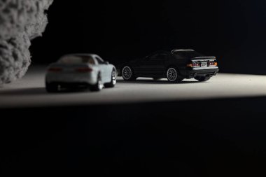 Mantova, İtalya - 3RD JANUARY 2025 - 1989 Mazda Savanna RX-7 'nin Ateşli Tekerlekleri ve Kibrit kutusu kopyaları ve beyaz bir tahtanın üzerinde beyaz bir kumaş parçasının yanında, uçurumun kenarındaki bir dağ yolunda yarış yapıyormuş gibi yapan Mitsubishi 3000 GT