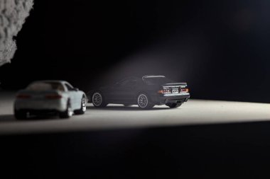 Mantova, İtalya - 3RD JANUARY 2025 - 1989 Mazda Savanna RX-7 'nin Ateşli Tekerlekleri ve Kibrit kutusu kopyaları ve beyaz bir tahtanın üzerinde beyaz bir kumaş parçasının yanında, uçurumun kenarındaki bir dağ yolunda yarış yapıyormuş gibi yapan Mitsubishi 3000 GT