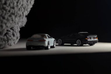 Mantova, İtalya - 3RD JANUARY 2025 - 1989 Mazda Savanna RX-7 'nin Ateşli Tekerlekleri ve Kibrit kutusu kopyaları ve beyaz bir tahtanın üzerinde beyaz bir kumaş parçasının yanında, uçurumun kenarındaki bir dağ yolunda yarış yapıyormuş gibi yapan Mitsubishi 3000 GT