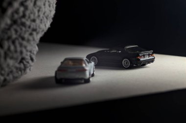 Mantova, İtalya - 3RD JANUARY 2025 - 1989 Mazda Savanna RX-7 'nin Ateşli Tekerlekleri ve Kibrit kutusu kopyaları ve beyaz bir tahtanın üzerinde beyaz bir kumaş parçasının yanında, uçurumun kenarındaki bir dağ yolunda yarış yapıyormuş gibi yapan Mitsubishi 3000 GT