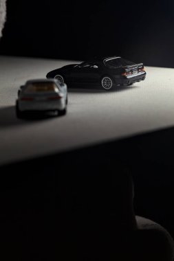 Mantova, İtalya - 3RD JANUARY 2025 - 1989 Mazda Savanna RX-7 'nin Ateşli Tekerlekleri ve Kibrit kutusu kopyaları ve beyaz bir tahtanın üzerinde beyaz bir kumaş parçasının yanında, uçurumun kenarındaki bir dağ yolunda yarış yapıyormuş gibi yapan Mitsubishi 3000 GT