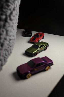 Mantova, İtalya - 3RD JANUARY 2025 - Nissan Skyline modellerinin çeşitli kopyaları, iki R30, bir GT-R R32 ve bir GT-R R33, beyaz bir tahta üzerinde, gri bir kumaş parçasının yanında, uçurumun kenarındaki bir dağ yolunda yarış yapıyormuş gibi yaparak