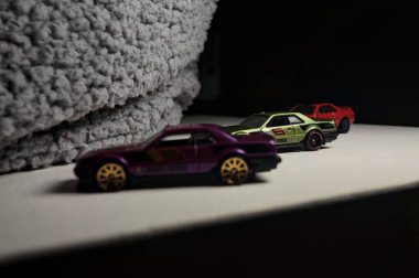 Mantova, İtalya - 3RD JANUARY 2025 - Nissan Skyline modellerinin çeşitli kopyaları, iki R30, bir GT-R R32 ve bir GT-R R33, beyaz bir tahta üzerinde, gri bir kumaş parçasının yanında, uçurumun kenarındaki bir dağ yolunda yarış yapıyormuş gibi yaparak