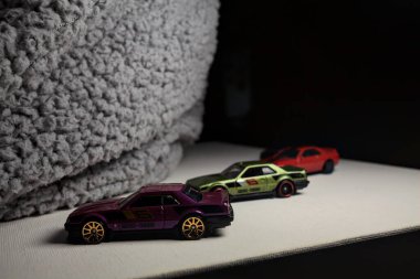 Mantova, İtalya - 3RD JANUARY 2025 - Nissan Skyline modellerinin çeşitli kopyaları, iki R30, bir GT-R R32 ve bir GT-R R33, beyaz bir tahta üzerinde, gri bir kumaş parçasının yanında, uçurumun kenarındaki bir dağ yolunda yarış yapıyormuş gibi yaparak