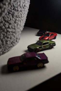 Mantova, İtalya - 3RD JANUARY 2025 - Nissan Skyline modellerinin çeşitli kopyaları, iki R30, bir GT-R R32 ve bir GT-R R33, beyaz bir tahta üzerinde, gri bir kumaş parçasının yanında, uçurumun kenarındaki bir dağ yolunda yarış yapıyormuş gibi yaparak