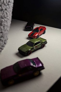 Mantova, İtalya - 3RD JANUARY 2025 - Nissan Skyline modellerinin çeşitli kopyaları, iki R30, bir GT-R R32 ve bir GT-R R33, beyaz bir tahta üzerinde, gri bir kumaş parçasının yanında, uçurumun kenarındaki bir dağ yolunda yarış yapıyormuş gibi yaparak