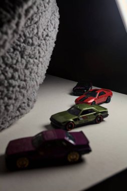 Mantova, İtalya - 3RD JANUARY 2025 - Nissan Skyline modellerinin çeşitli kopyaları, iki R30, bir GT-R R32 ve bir GT-R R33, beyaz bir tahta üzerinde, gri bir kumaş parçasının yanında, uçurumun kenarındaki bir dağ yolunda yarış yapıyormuş gibi yaparak