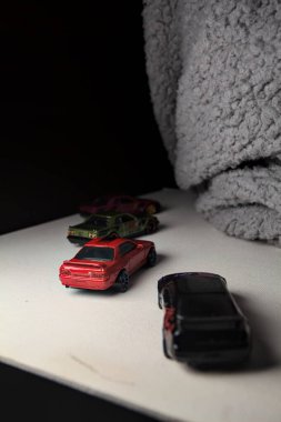 Mantova, İtalya - 3RD JANUARY 2025 - Nissan Skyline modellerinin çeşitli kopyaları, iki R30, bir GT-R R32 ve bir GT-R R33, beyaz bir tahta üzerinde, gri bir kumaş parçasının yanında, uçurumun kenarındaki bir dağ yolunda yarış yapıyormuş gibi yaparak