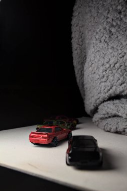 Mantova, İtalya - 3RD JANUARY 2025 - Nissan Skyline modellerinin çeşitli kopyaları, iki R30, bir GT-R R32 ve bir GT-R R33, beyaz bir tahta üzerinde, gri bir kumaş parçasının yanında, uçurumun kenarındaki bir dağ yolunda yarış yapıyormuş gibi yaparak