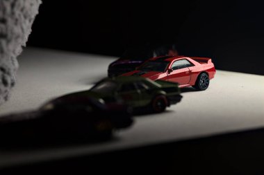 Mantova, İtalya - 3RD JANUARY 2025 - Nissan Skyline modellerinin çeşitli kopyaları, iki R30, bir GT-R R32 ve bir GT-R R33, beyaz bir tahta üzerinde, gri bir kumaş parçasının yanında, uçurumun kenarındaki bir dağ yolunda yarış yapıyormuş gibi yaparak