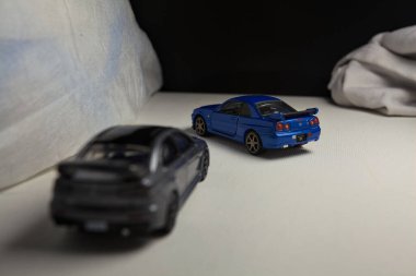 Mantova, İtalya - 4. JANUARY 2025 - Nissan Skyline GT-R V-Spec Nur II ve Mitsubishi Lancer Evolution 'ın beyaz panoda kopyaları, beyaz kumaşlarla çevrelenmiş, yolda bir eğri yapıyor ve aralarında bir yarış varmış gibi davranıyorlar.