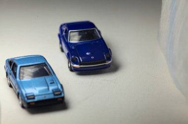 Mantova, İtalya - 4. HAZİRAN 2025 Takara Tomy, beyaz kumaş rulolarla çevrili, farklı zaman dilimli iki Nissan Fairlady Z 'nin kopyasıdır.