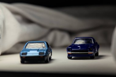 Mantova, İtalya - 4. HAZİRAN 2025 Takara Tomy, beyaz kumaş rulolarla çevrili, farklı zaman dilimli iki Nissan Fairlady Z 'nin kopyasıdır.