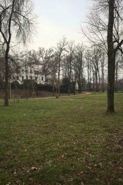 Kışın bulutlu bir günde, İtalya 'nın bir kasabasında ağaçlarla çevrili bir binanın yanındaki kavak ağaçlarıyla çevrili bir patikaya tırmanmak.