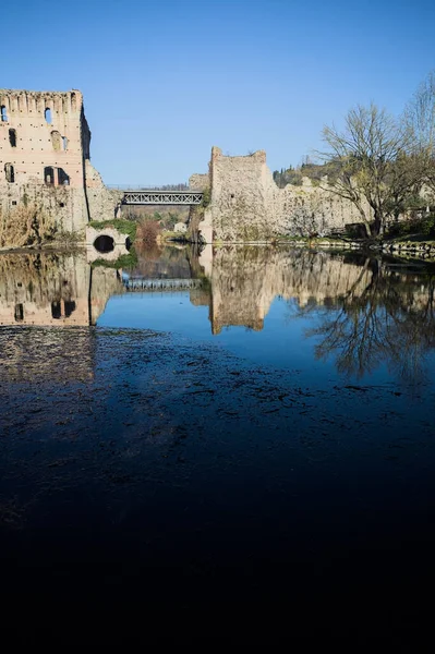 Bir yol köprüsü arasında, içinden geçen ve bir sınır duvarının kalıntıları üzerinde, kışın güneşli bir günde uzaktan görülen yapıyı yansıtan bir nehrin üzerindeki kaleler.
