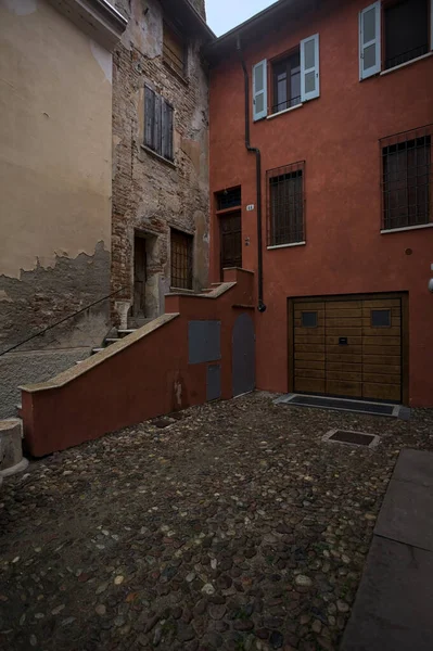 Bulutlu bir günde, iki binanın köşesindeki bir İtalyan kasabasının ara sokağında, cepheye açılan bir kapıya çıkan merdiven.