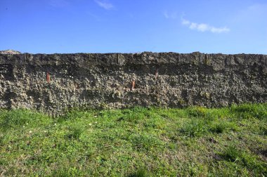 Arka planda gökyüzü olan çimenlikte beton duvar