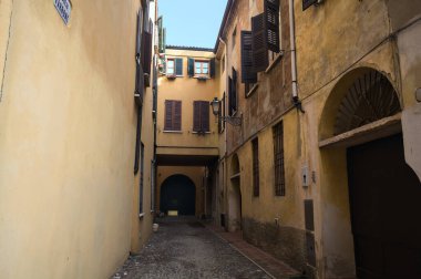 Narrow and cobbled alley, with an overhead passage, partially in the shade, in an italian town